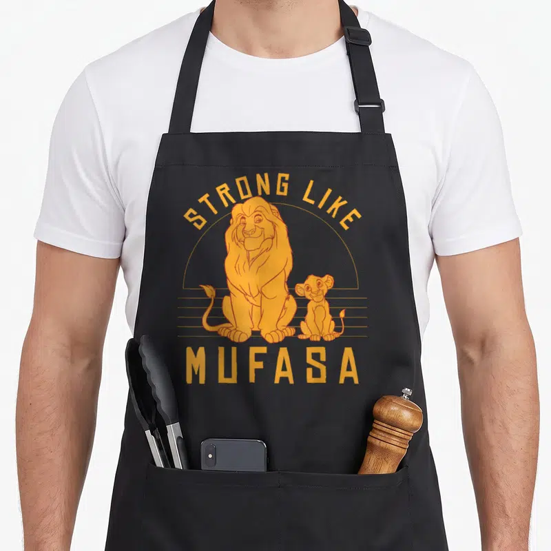 Tablier de cuisine noir avec illustration orange de Simba et Mufasa et texte Strong Like Mufasa.