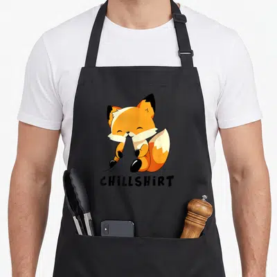 Tablier de cuisine noir avec un renard orange en pyjama et le texte Chillshirt imprimé en bas.