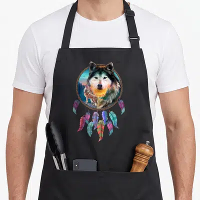 Tablier de cuisine noir avec un attrape-rêves illustrant un loup aux yeux perçants et des plumes multicolores.