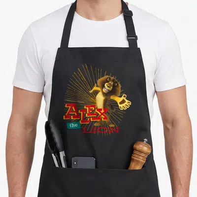 Tablier de cuisine noir avec Alex the Lion illustration et texte rouge rayonnant.