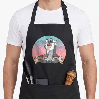 Tablier de cuisine noir avec Rafiki en méditation assis en tailleur devant un coucher de soleil africain.