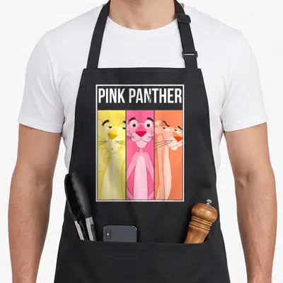 Tablier de cuisine noir avec une illustration de la Panthère Rose sur trois fonds colorés distincts.