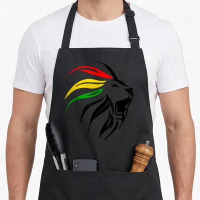 Tablier de cuisine noir avec tête de lion aux dreadlocks rouges jaunes et vertes sur fond uni.