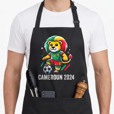 Tablier de cuisine noir avec un lion footballeur aux couleurs du Cameroun et le texte Cameroun 2024 en bas.