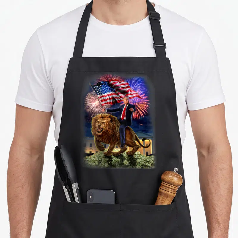 Tablier de cuisine noir avec Donald Trump chevauchant un lion féroce tenant une American flag devant la Maison Blanche.