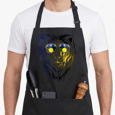 Tablier de cuisine noir avec illustration d'un lion aux verres réfléchissant des symboles dorés et bleus.