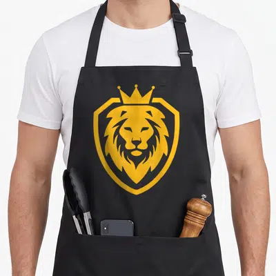 Tablier de cuisine noir avec un lion couronné dans un écu doré style logo graphique