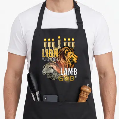 Tablier de cuisine noir avec illustration d'un lion et d'un agneau sous un menorah doré, texte Lion of Judah et Lamb of God.