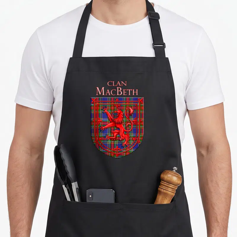 Tablier de cuisine noir avec un blason Clan MacBeth affichant un lion rampant rouge sur fond tartan écossais multicolore.