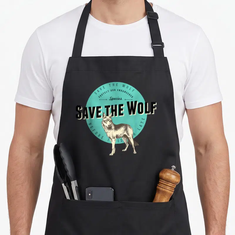 Tablier de cuisine noir avec illustration vintage d'un loup et texte Save the Wolf sur fond turquoise circulaire.