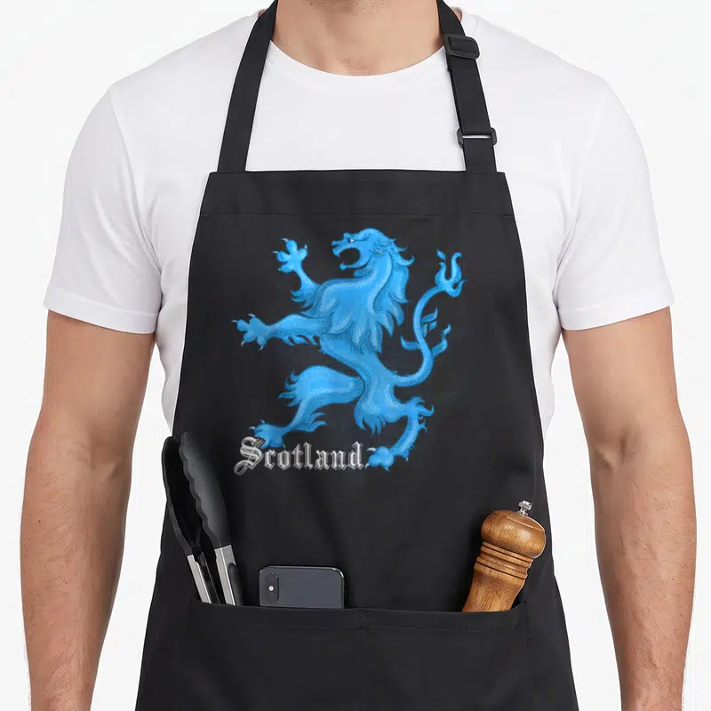 Tablier de cuisine noir avec illustration bleue d'un lion écossais rampant et le texte Scotland en typographie gothique blanche.
