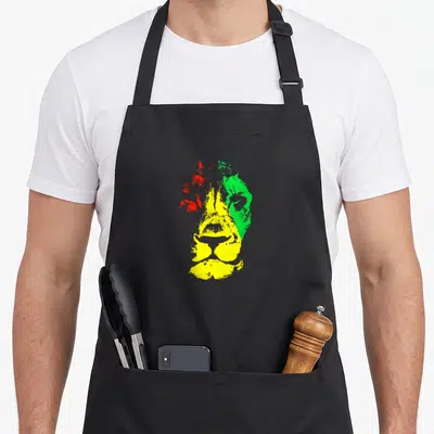 Tablier de cuisine noir avec une illustration stylisée d'une tête de lion aux couleurs vives et au look rasta.