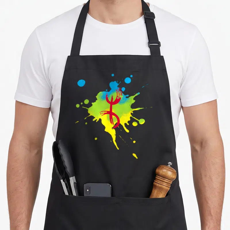Tablier de cuisine noir avec le Symbole Yaz Amazigh rouge sur une éclaboussure jaune verte et bleue.