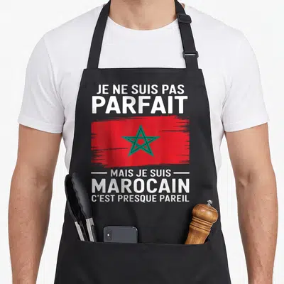 Tablier de cuisine noir avec drapeau marocain rouge et étoile verte, texte blanc humoristique sur fond uni.