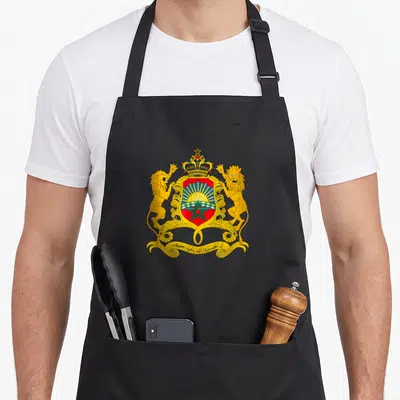 Tablier de cuisine noir avec emblème royal marocain, lions dorés et étoile verte sur fond rouge.