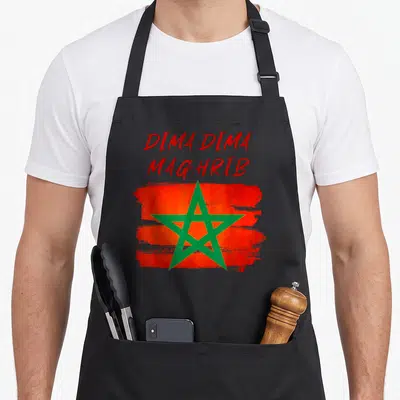 Tablier de cuisine noir avec inscription Dima Dima Maghrib et étoile verte sur fond rouge texturé.