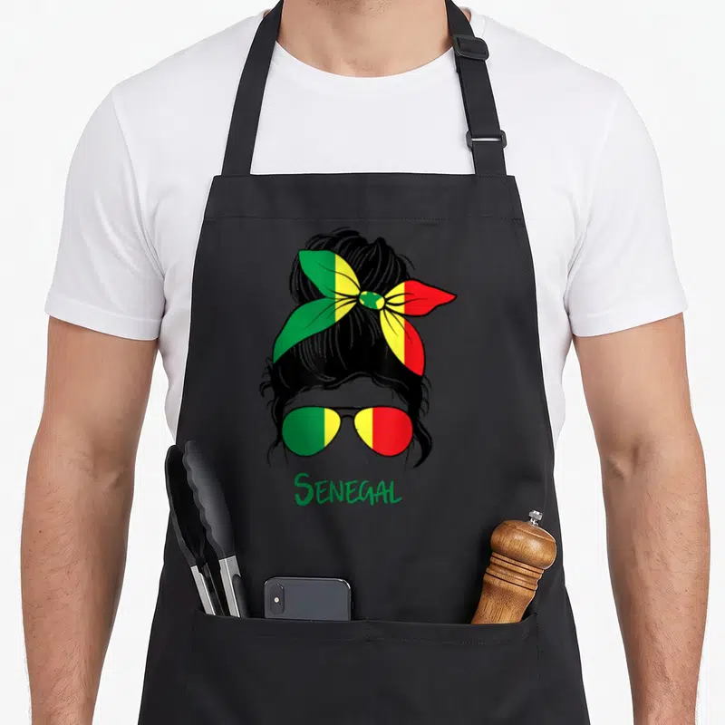 Tablier de cuisine noir avec illustration d'une femme au foulard tricolore et lunettes aux mêmes couleurs.
