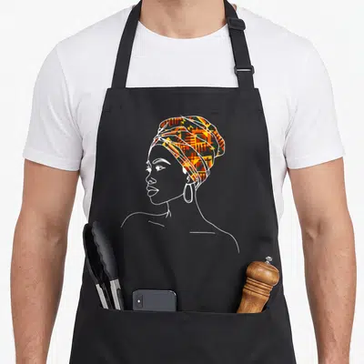 Tablier de cuisine noir avec illustration femme au foulard kente tribal africain aux motifs géométriques orange et vert.