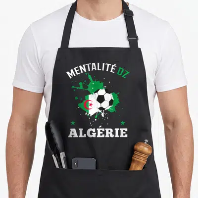 Tablier de cuisine noir avec un ballon de football intégrant le drapeau algérien et des éclaboussures vertes.