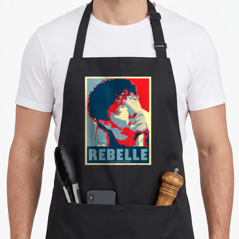 Tablier de cuisine noir avec illustration graphique rouge et bleue de Matoub Lounes et le mot REBELLE en bas.