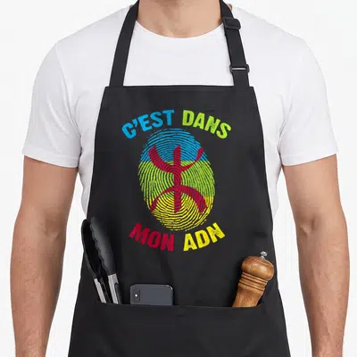 Tablier de cuisine noir avec une empreinte digitale multicolore portant le symbole Tifinagh et le texte C'est dans mon ADN.
