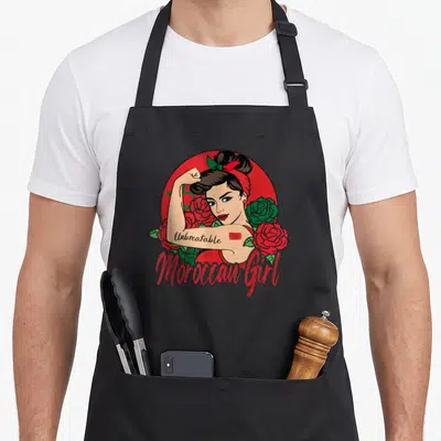 Tablier de cuisine noir avec illustration d'une femme au poing levé entourée de roses rouges et vertes.