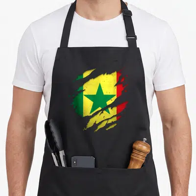Tablier de cuisine noir avec illustration du drapeau sénégalais aux couleurs vives et effet de texture usée au centre.
