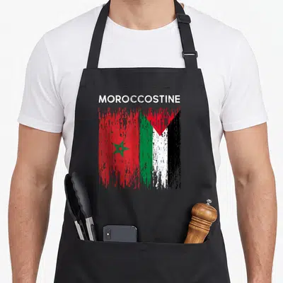 Tablier de cuisine noir avec l'inscription Moroccostine et un drapeau combinant les couleurs et symboles marocain et palestinien en style vintage.