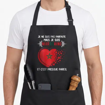 Tablier de cuisine noir avec un grand cœur rouge à l'étoile verte et du texte humoristique en blanc et vert.