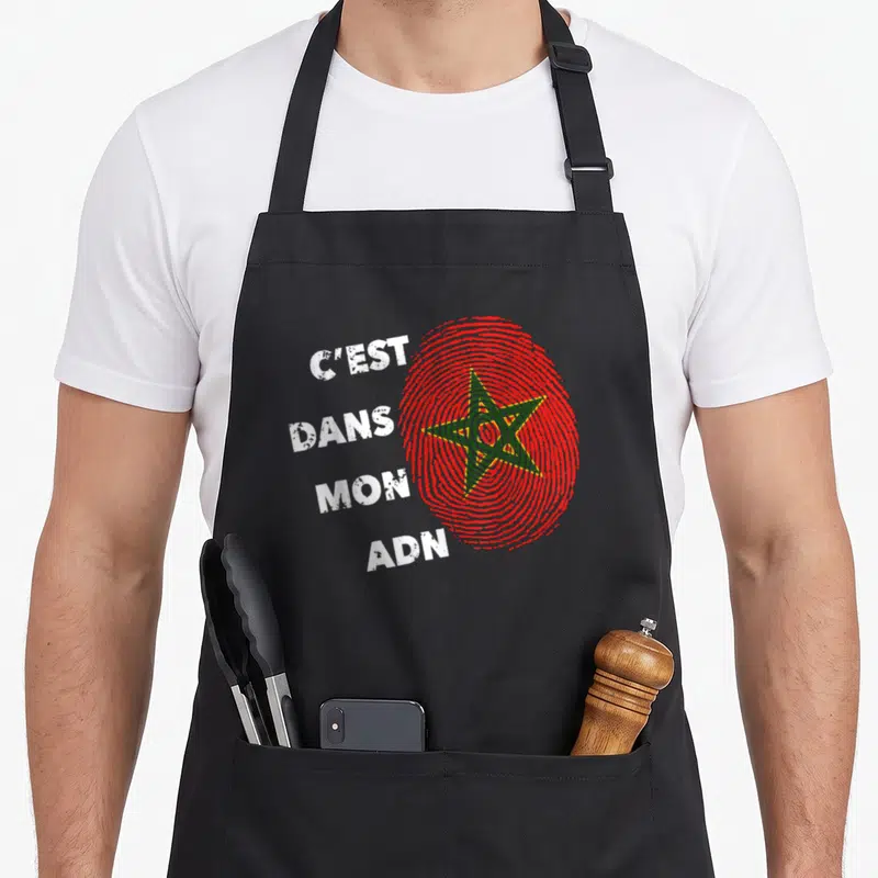 Tablier de cuisine noir avec une empreinte digitale rouge contenant une étoile verte et le texte blanc C'est dans mon ADN.