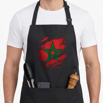 Tablier de cuisine noir avec un drapeau marocain rouge et vert stylisé effet déchirure.