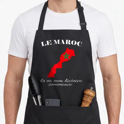 Tablier de cuisine noir avec une carte rouge du Maroc, une étoile verte et un texte blanc évoquant l'histoire personnelle.