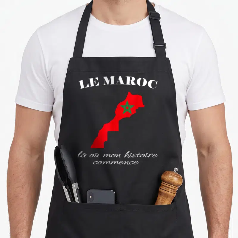 Tablier de cuisine noir avec une carte rouge du Maroc, une étoile verte et un texte blanc évoquant l'histoire personnelle.