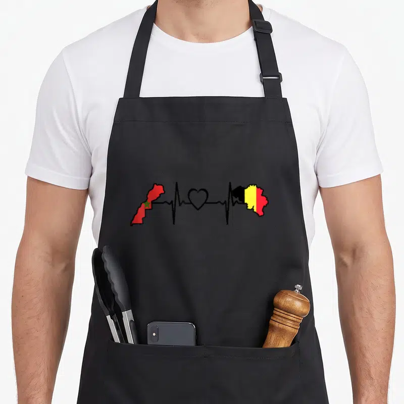 Tablier de cuisine noir avec une illustration de battement de cœur marocain belge reliant deux cartes aux couleurs nationales.
