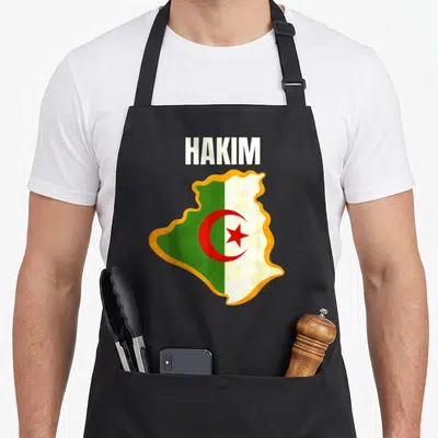 Tablier de cuisine noir avec une carte de l'Algrie portant le nom Hakim et les couleurs du drapeau national.