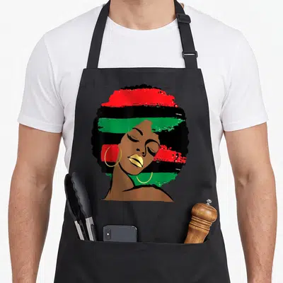 Tablier de cuisine noir avec portrait stylisé d'une femme afro aux lèvres dorées et cheveux aux couleurs du drapeau pan-africain.