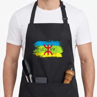 Tablier de cuisine noir avec drapeau amazigh bleu vert jaune et symboles tifinagh rouges au centre.