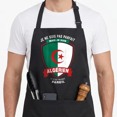 Tablier de cuisine noir avec un blason vert et blanc portant la mention Je ne suis pas parfait mais je suis Algérien et c'est presque pareil.