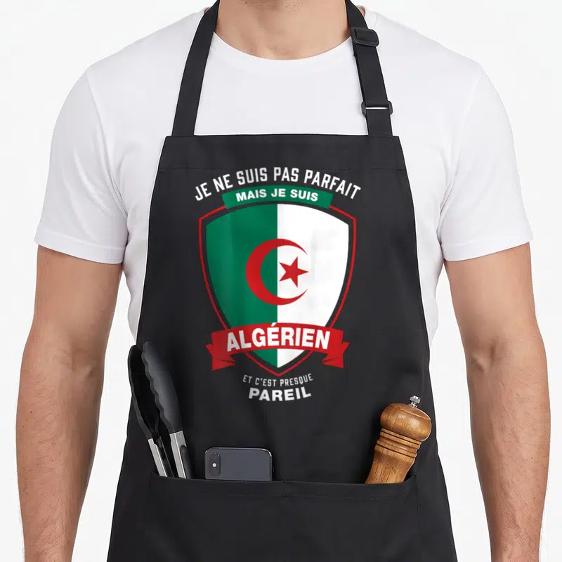 Tablier de cuisine noir avec un blason vert et blanc portant la mention Je ne suis pas parfait mais je suis Algérien et c'est presque pareil.
