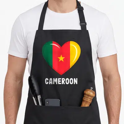 Tablier de cuisine noir avec un grand cœur aux couleurs du drapeau camerounais et l'inscription CAMEROON en blanc.