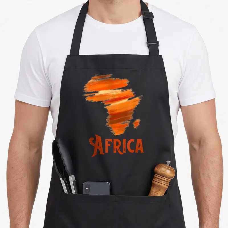 Tablier de cuisine noir avec carte Afrique stylisée en touches orange et le mot Africa imprimé en bas.