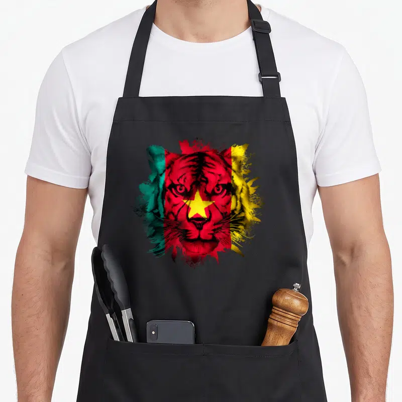 Tablier de cuisine noir avec un lion aux couleurs du drapeau camerounais et une étoile jaune centrale.