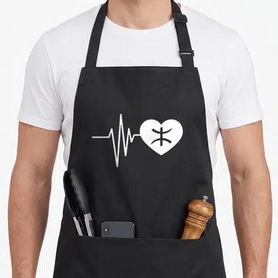 Tablier de cuisine noir avec un rythme cardiaque blanc formant un cœur yaz amazigh au centre.