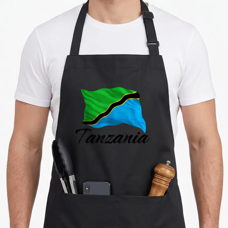 Tablier de cuisine noir avec le drapeau de Tanzanie vert bleu et noir et le mot Tanzania en calligraphie.