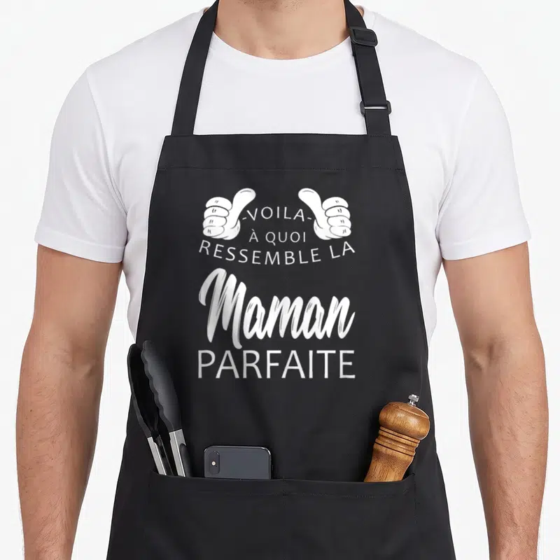 Tablier de cuisine noir avec inscription blanche « Voilà à quoi ressemble la Maman Parfaite » surmontée de deux mains faisant un signe de pouce levé.