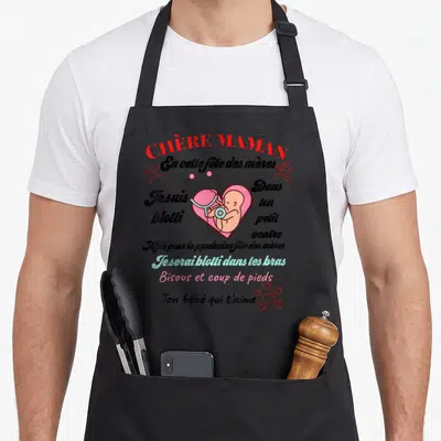 Tablier de cuisine noir avec inscription Chère Maman et illustration d'un cœur rose contenant un fœtus avec un stéthoscope.