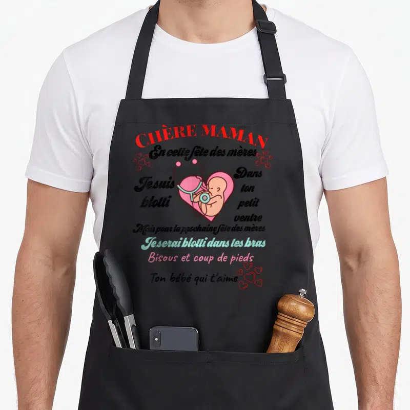 Tablier de cuisine noir avec inscription Chère Maman et illustration d'un cœur rose contenant un fœtus avec un stéthoscope.