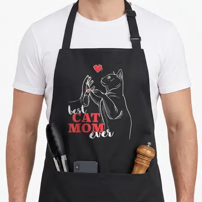 Tablier de cuisine noir avec illustration d'un chat tenant une main et le texte best cat mom ever en rouge et blanc.