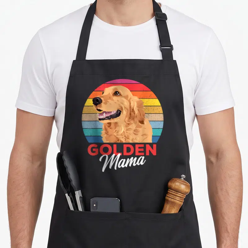 Tablier de cuisine noir avec illustration d'un golden retriever souriant et le texte Golden Mama en lettres rouges et blanches.