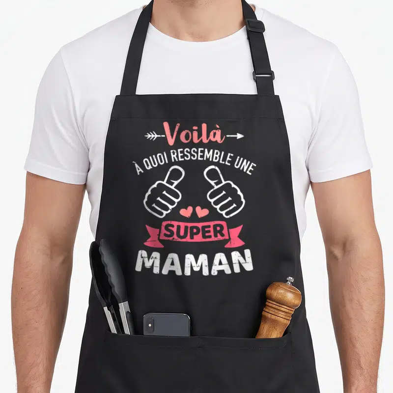 Tablier de cuisine noir avec inscription Voilà à quoi ressemble une super maman, deux pouces levés et cœurs roses sur fond blanc.